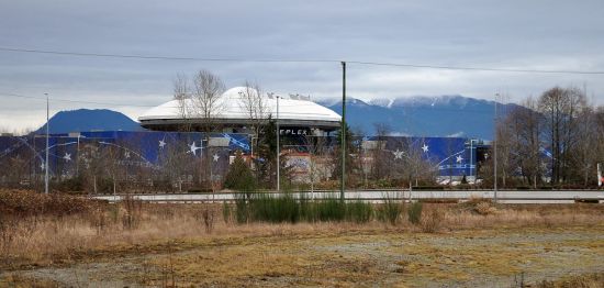 Looking north across undeveloped freeway lands to the Colossus Cinema and the Golden Ears peaks.