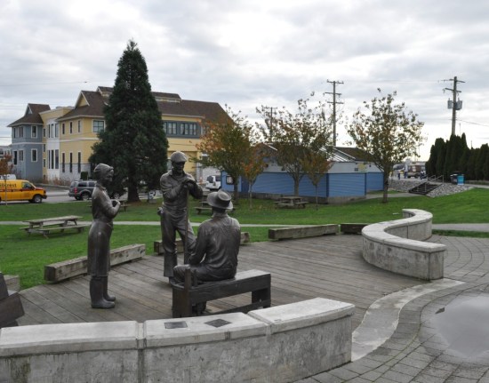 A grouping of statues of fish cannery workers outside the Cannery museum. The two-storey building in the background is recent. 